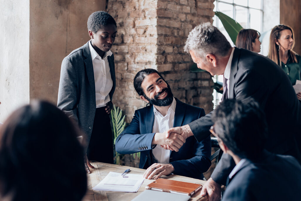 Business team welcoming a new colleague with a handshake during an onboarding meeting in a modern office.